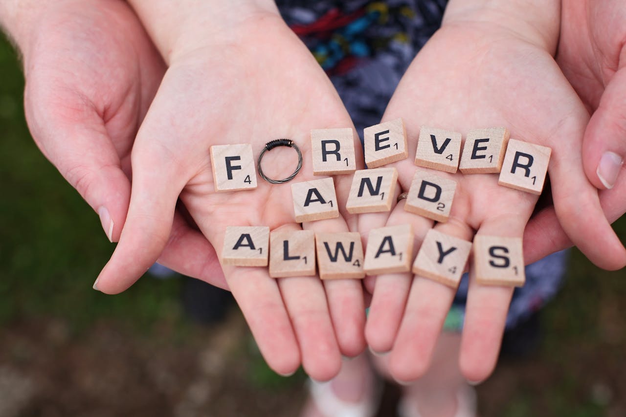 Hands holding forever and always in Scrabble letters, symbolizing eternal love.